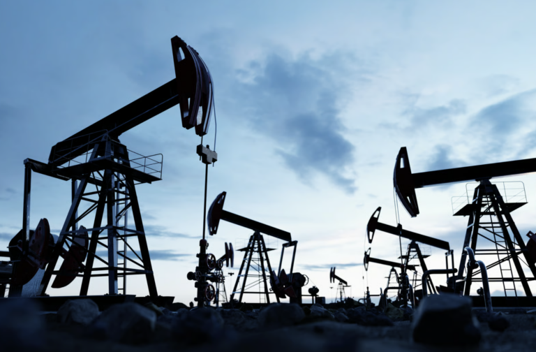 silhouetted oil field against a cloudy blue sky